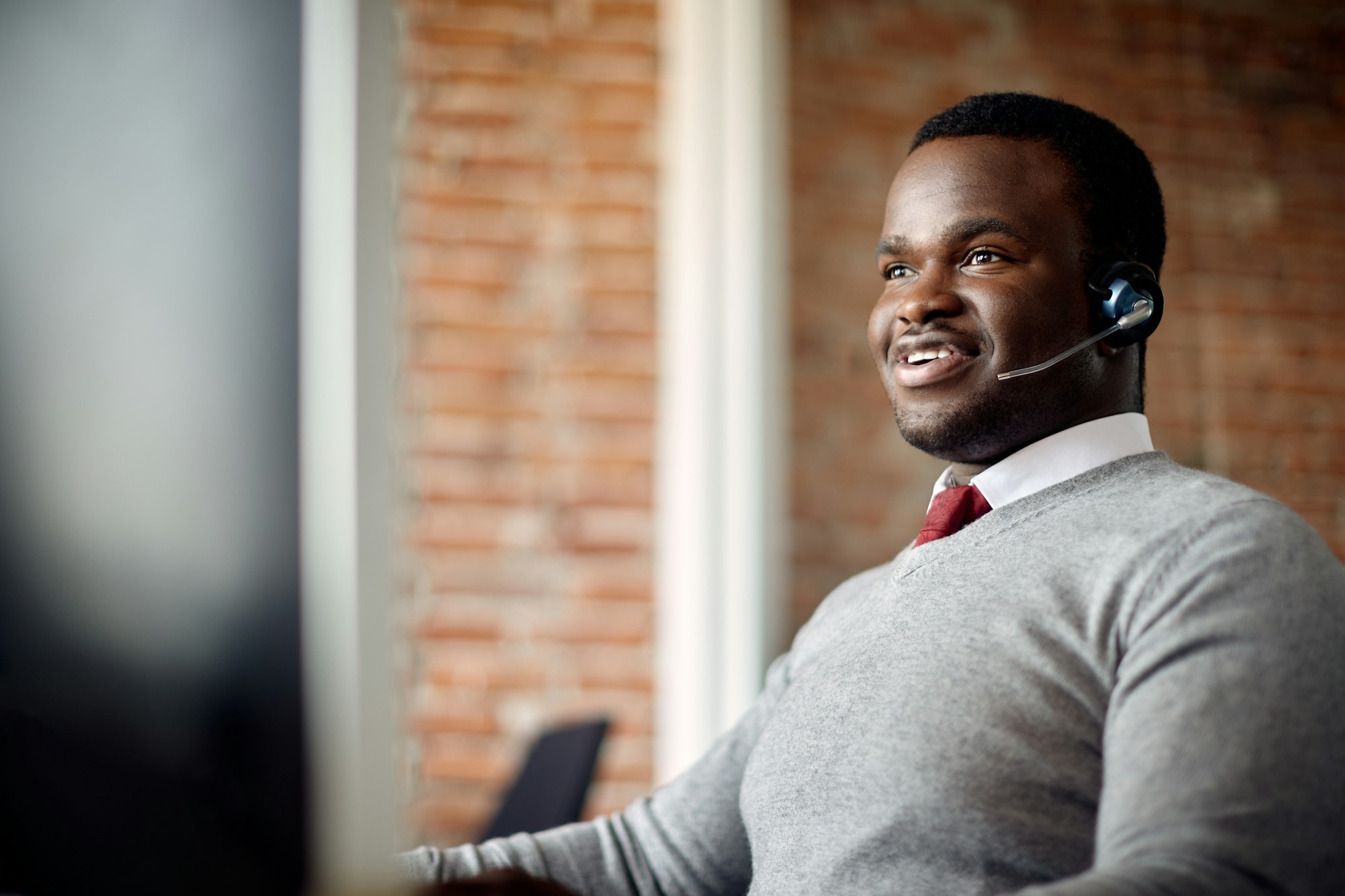 Happy black customer service operator working on desktop PC in the office.